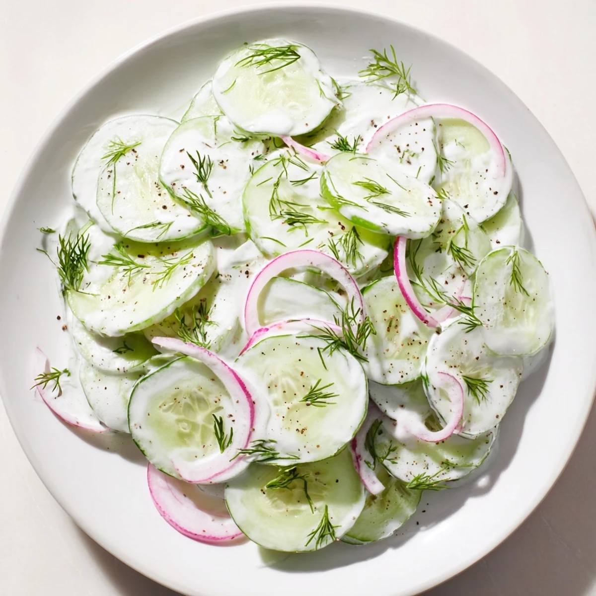 Tangy Omas German Cucumber Salad with vibrant green cucumber slices and creamy dressing.