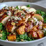 Helles Herbst-Süßkartoffel-Schüssel mit geröstetem Hähnchen, Äpfeln und Ziegenkäse auf einem rustikalen Tisch.