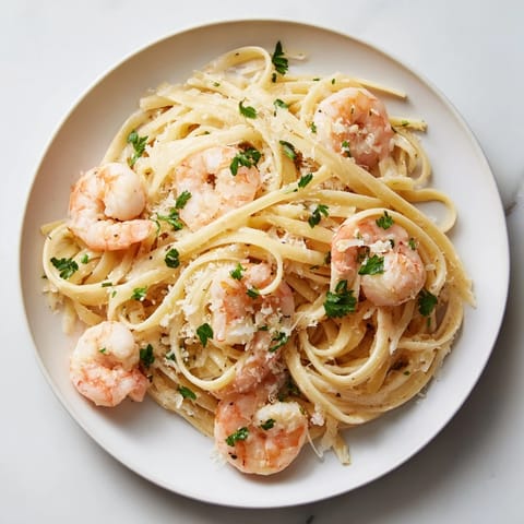 Tossed linguine coated in creamy garlic sauce, featuring plump pink shrimp and a sprinkle of red pepper flakes for warmth.