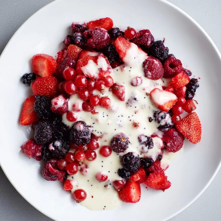 A close-up of fresh Rote Grütze, the berry compote, alongside rich homemade vanilla sauce.