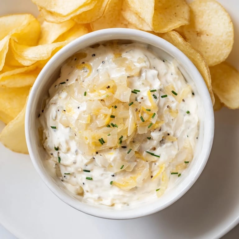 A close-up of a bowl of potato chips and onion dip, ready for dipping and enjoying.